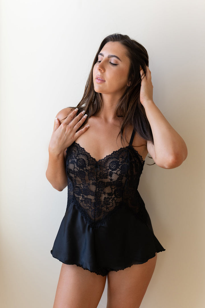 Woman wearing a black lace lingerie set against a plain background