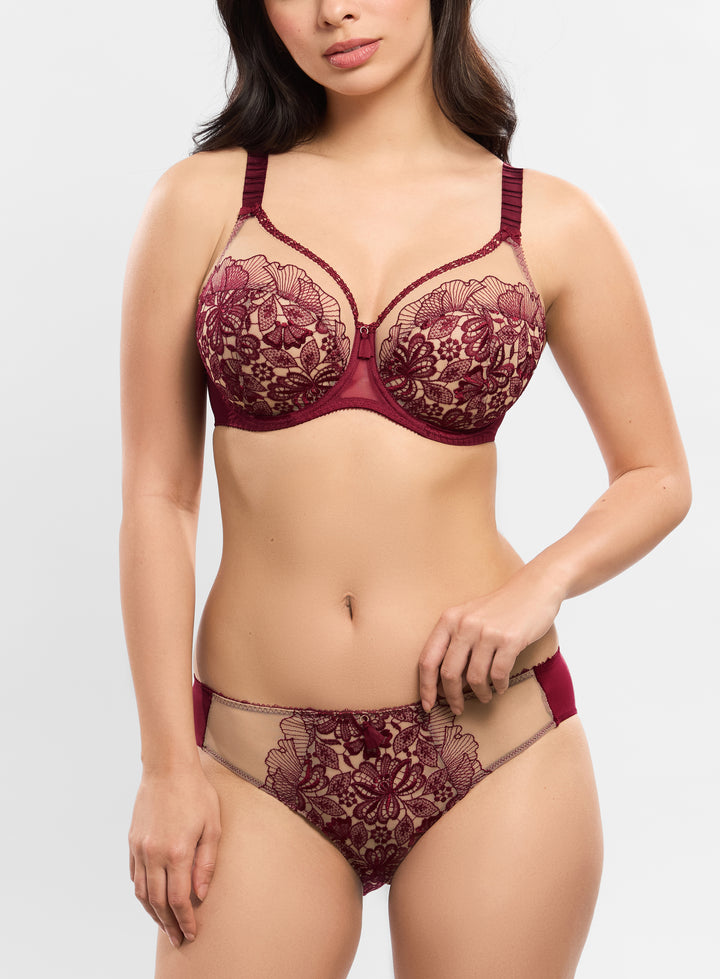 Woman wearing a burgundy lace lingerie set on a plain background