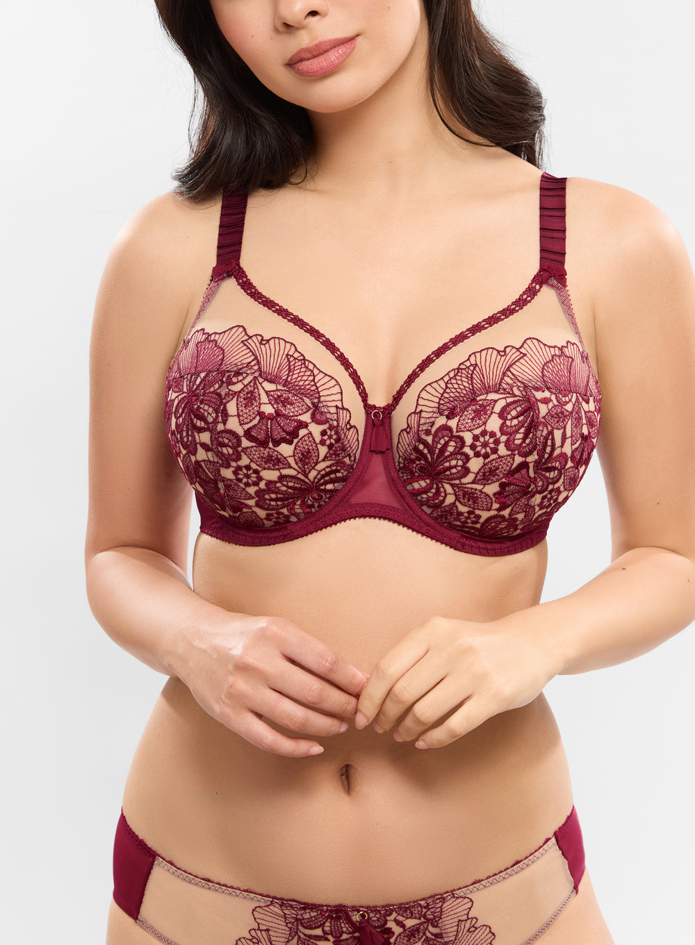Woman wearing a burgundy lace bra and panties set on a white background
