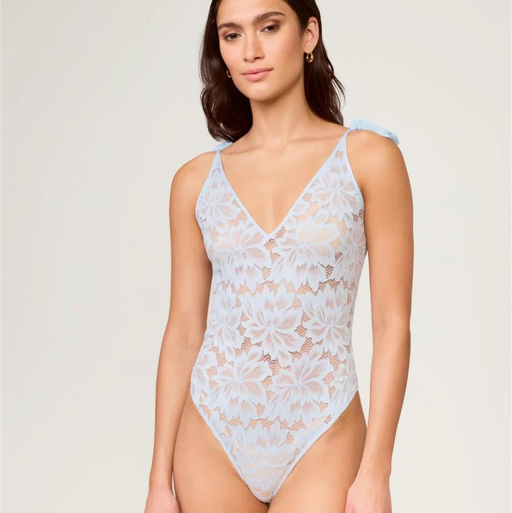 Woman wearing a light blue lace bodysuit on a white background