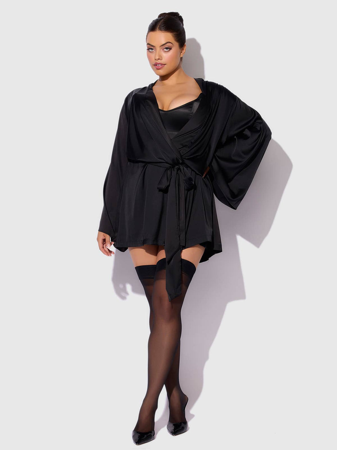 Woman wearing a black robe and stockings against a white background