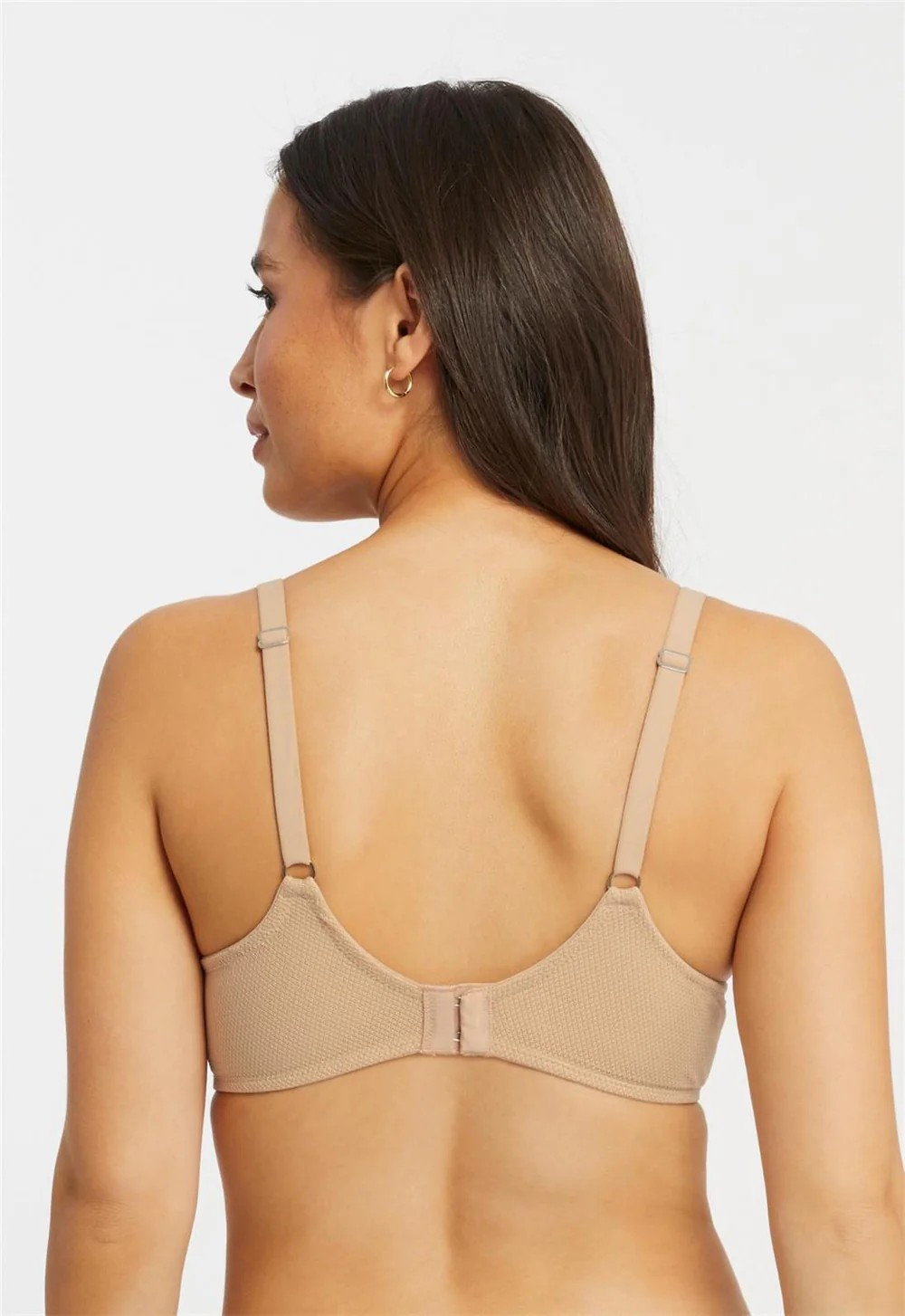 Woman wearing a beige bra against a plain background