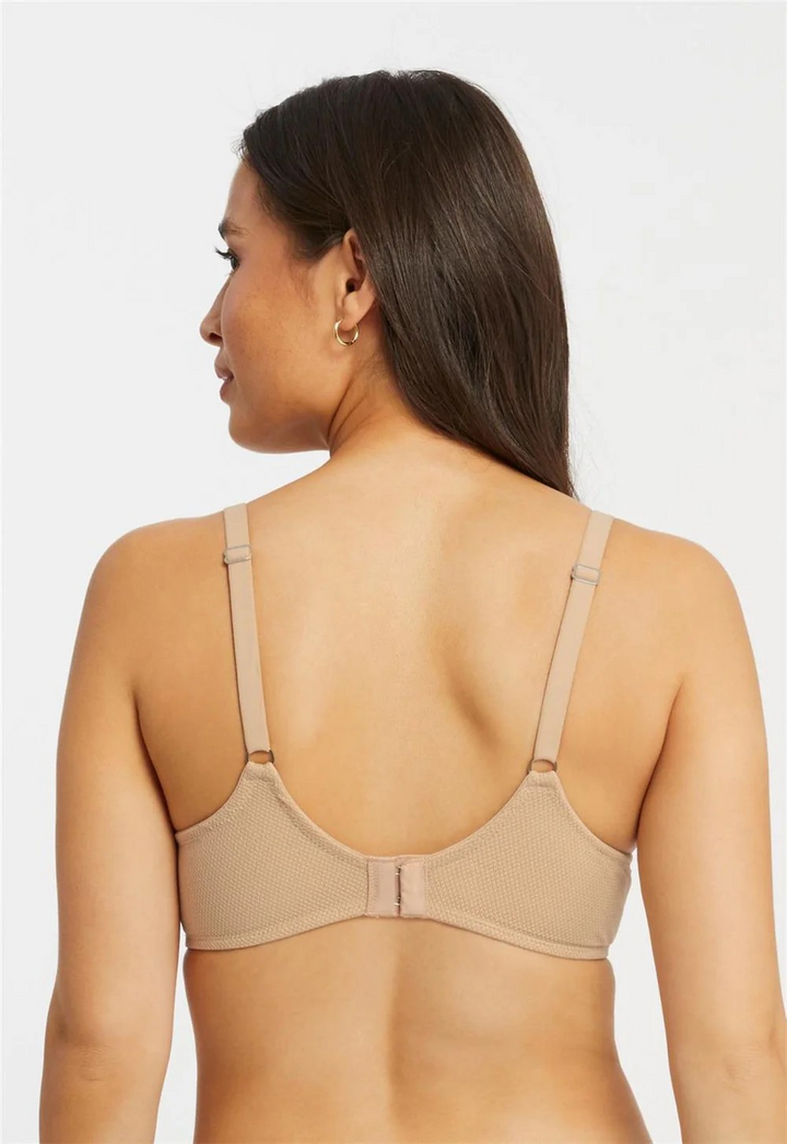 Woman wearing a beige bra against a plain background