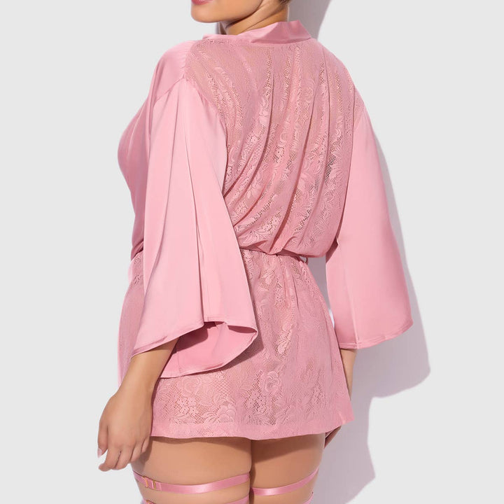 Woman wearing a pink satin and lace short robe with sheer stockings on a white background
