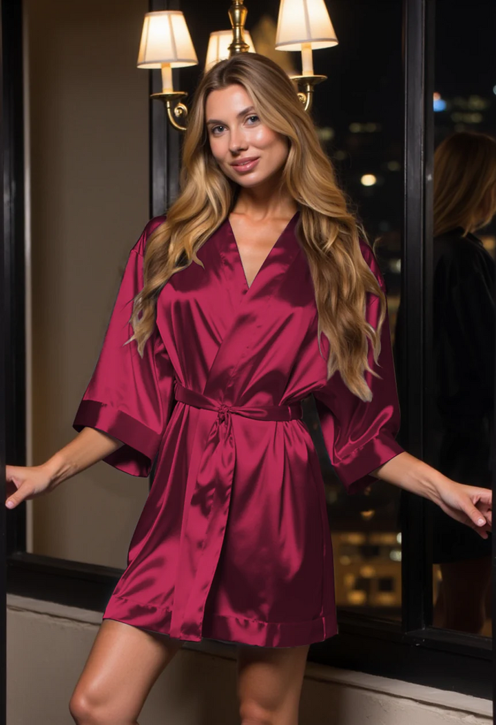 Woman wearing a burgundy satin robe in a dimly lit room.