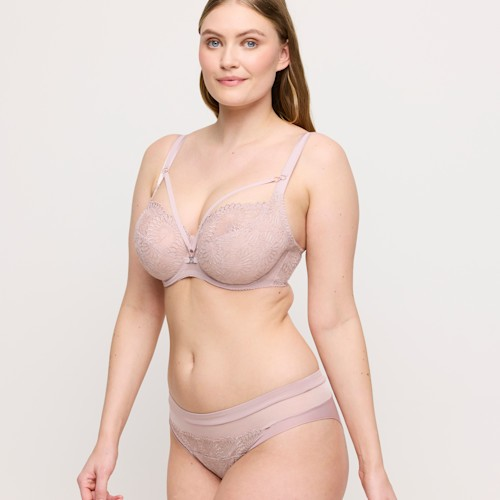 Woman wearing a light pink bra and panties set on a plain background