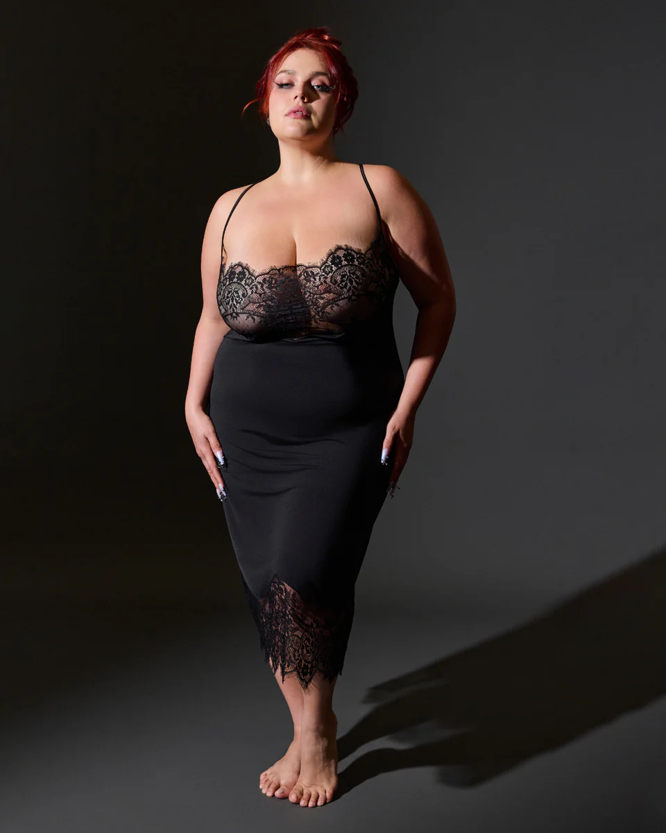 Woman wearing a black lace slip against a dark background