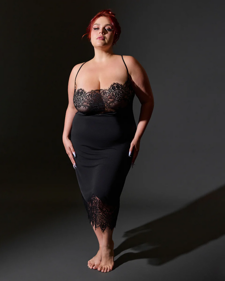 Woman wearing a black lace slip against a dark background