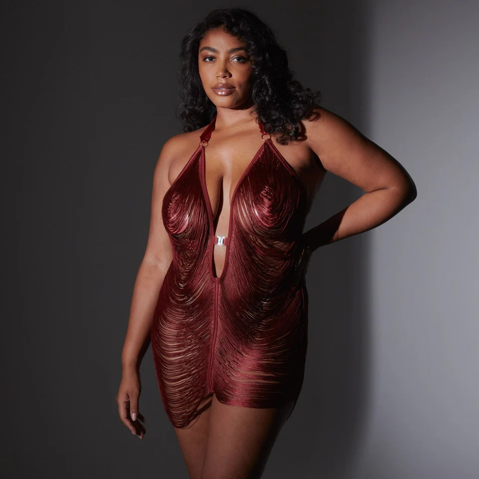 Woman wearing a burgundy, sheer fringe slip against a gray background