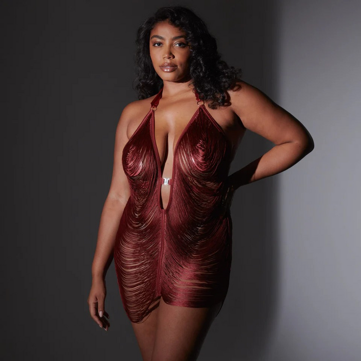 Woman wearing a burgundy, sheer fringe slip against a gray background