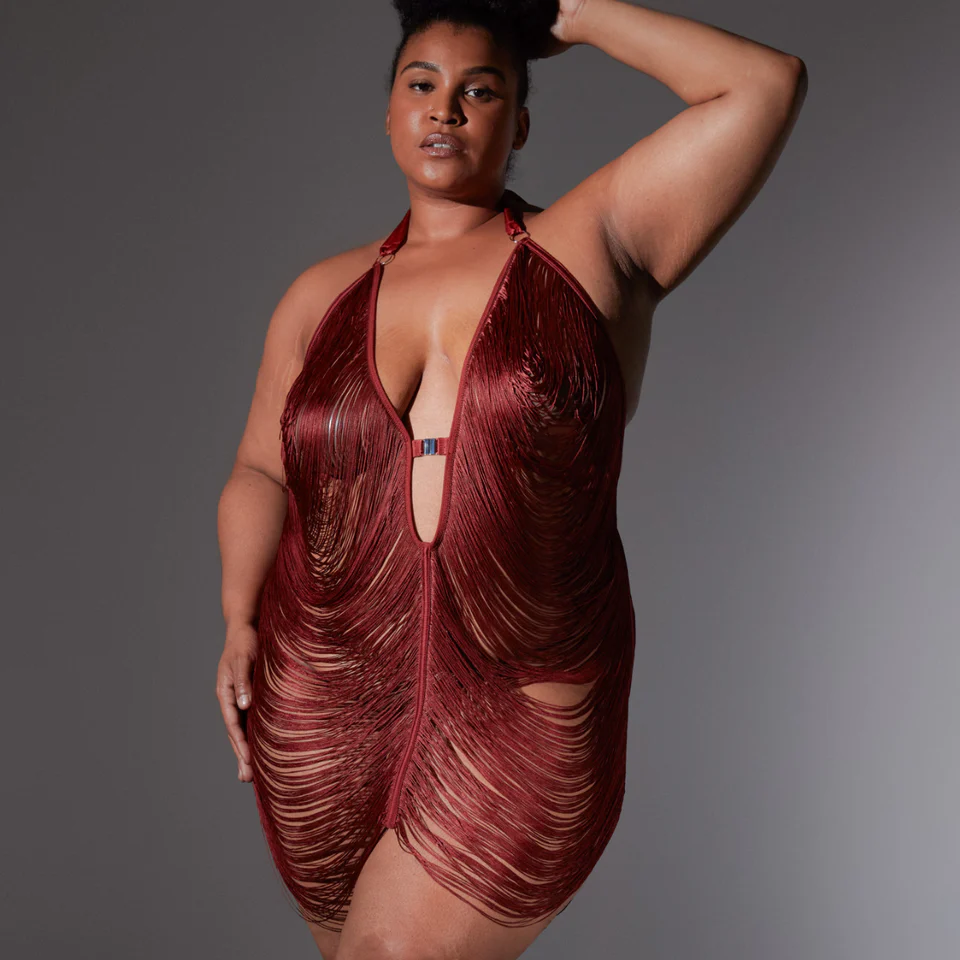 Woman wearing a red, fringe halter slip against a gray background