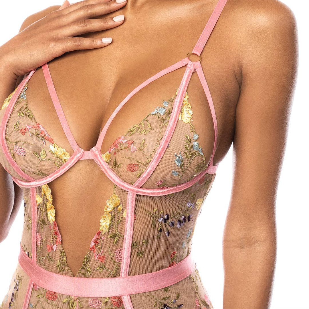 Model wearing a floral lingerie set with pink straps on a white background