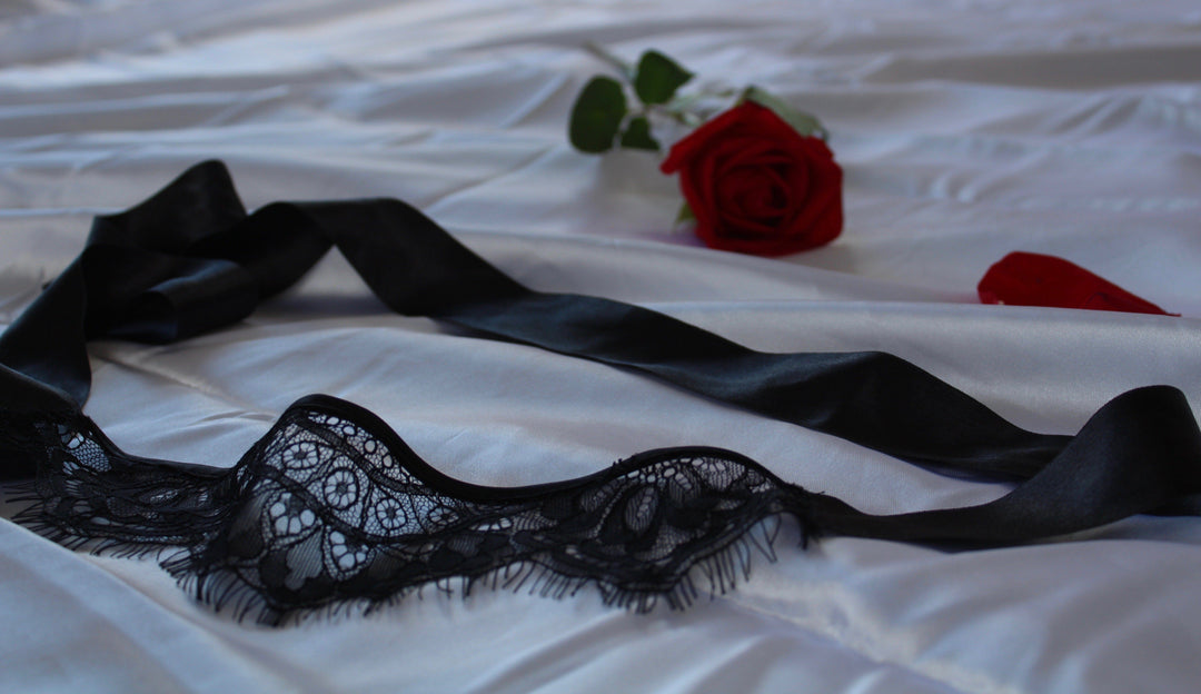 Black lace lingerie set on a white surface with red roses.