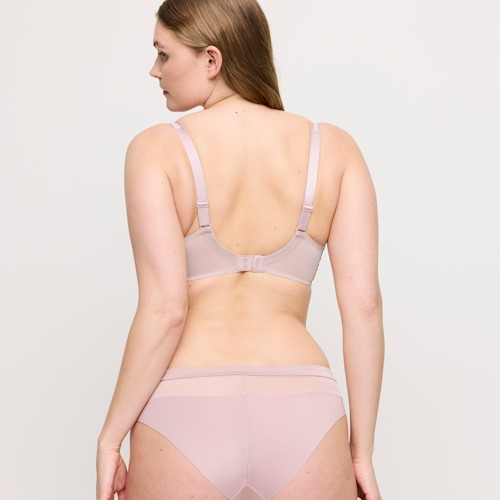Woman wearing a light pink bra and underwear set on a plain background