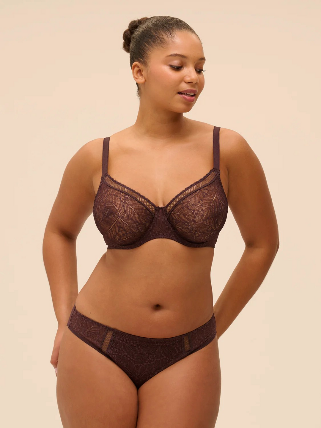 Simone Perele french lingerie Woman wearing a dark brown lace bra and panties set against a beige background